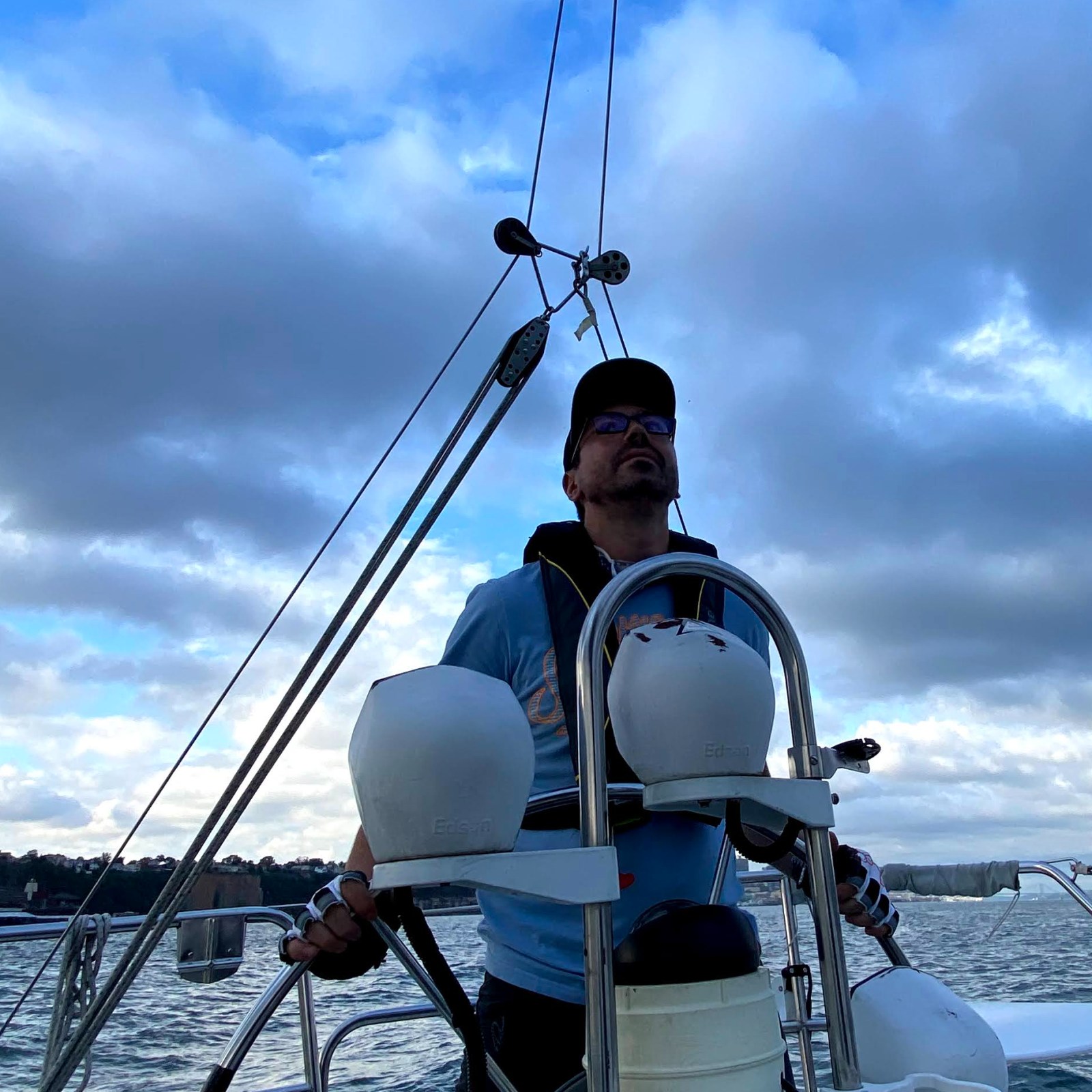 Truman at the helm of a sailboat, looking up at the sails